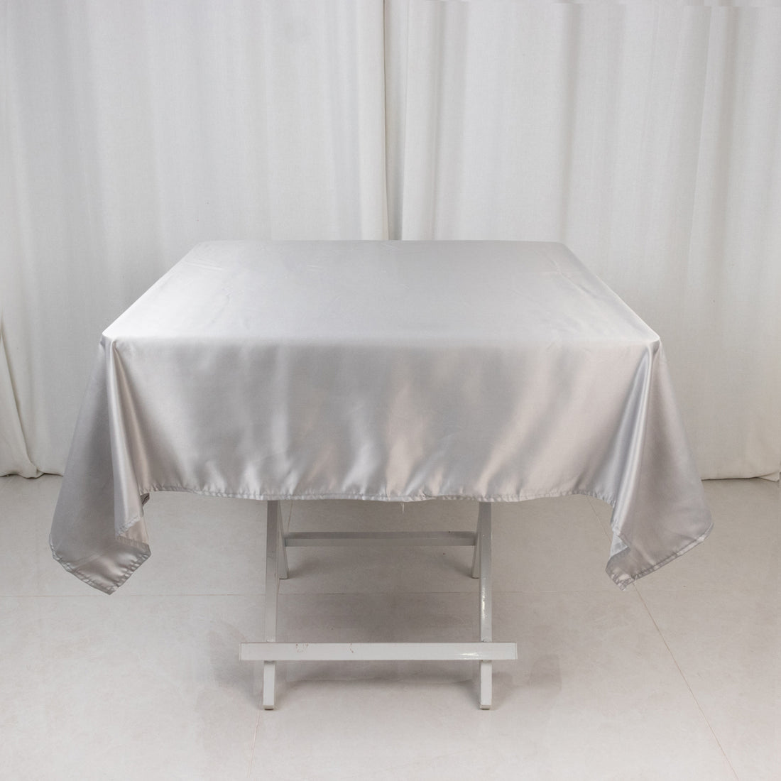 Silver satin tablecloth draped over a white table