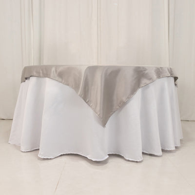 Elegant round table with white cloth and silver satin overlay