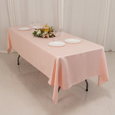 Pink tablecloth draped over a table set with plates and floral decor.