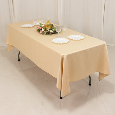 Beige tablecloth draped over a table set with plates and glasses.