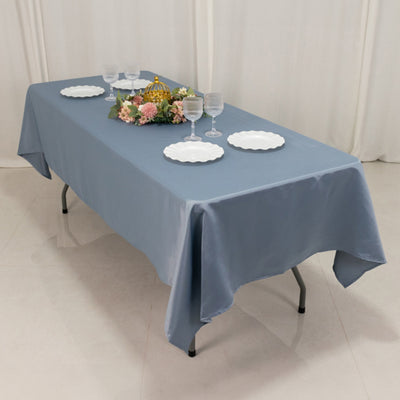 Blue tablecloth on a dining table with plates and floral centerpiece.