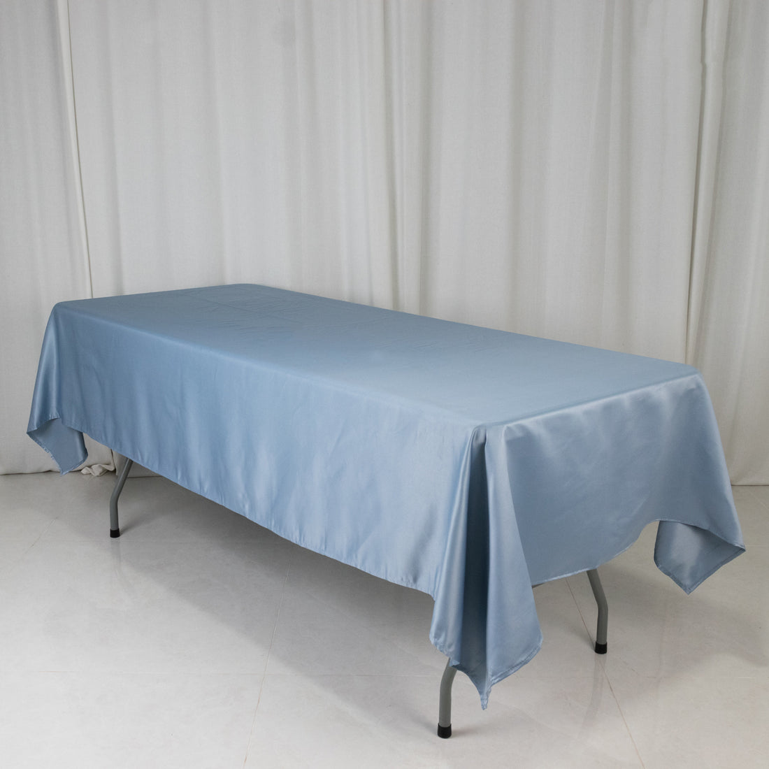 Blue satin tablecloth draped over a table on a plain backdrop.