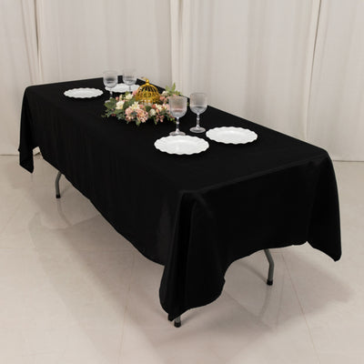Black tablecloth on a table set with plates and glasses.