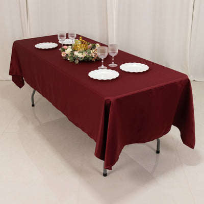 Burgundy tablecloth draped over a table set for dining with plates and glasses.
