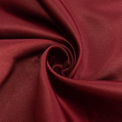 Burgundy satin fabric swirl, showcasing smooth texture and rich color.