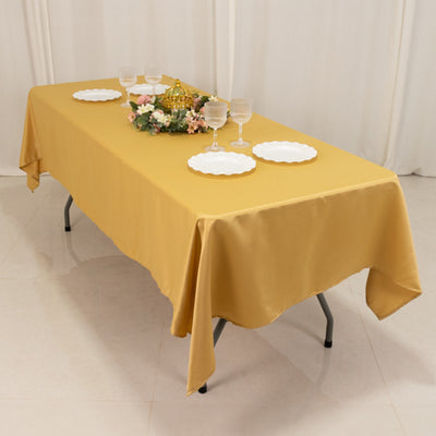 Yellow tablecloth draped over a table set with plates and a floral centerpiece.