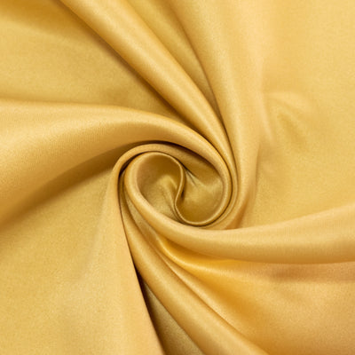 Golden satin fabric swirl texture close-up shot.