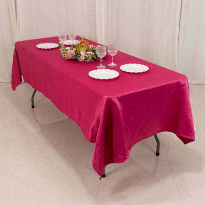 Pink tablecloth draped over a table set with plates and glasses.