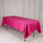 Pink satin tablecloth draped over a folding table in a studio setting.