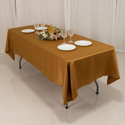 Brown tablecloth draped over a table set with plates and a floral centerpiece.