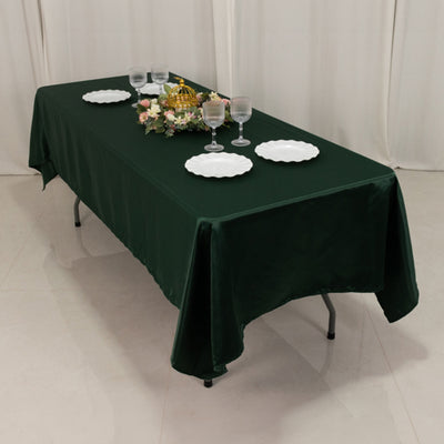 Green tablecloth on a table set with plates and glasses, floral centerpiece.