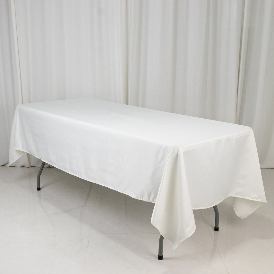 White tablecloth draped over a rectangular table in a studio setting.