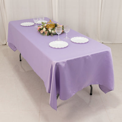 Purple tablecloth draped over a table set with plates and decorative centerpiece.