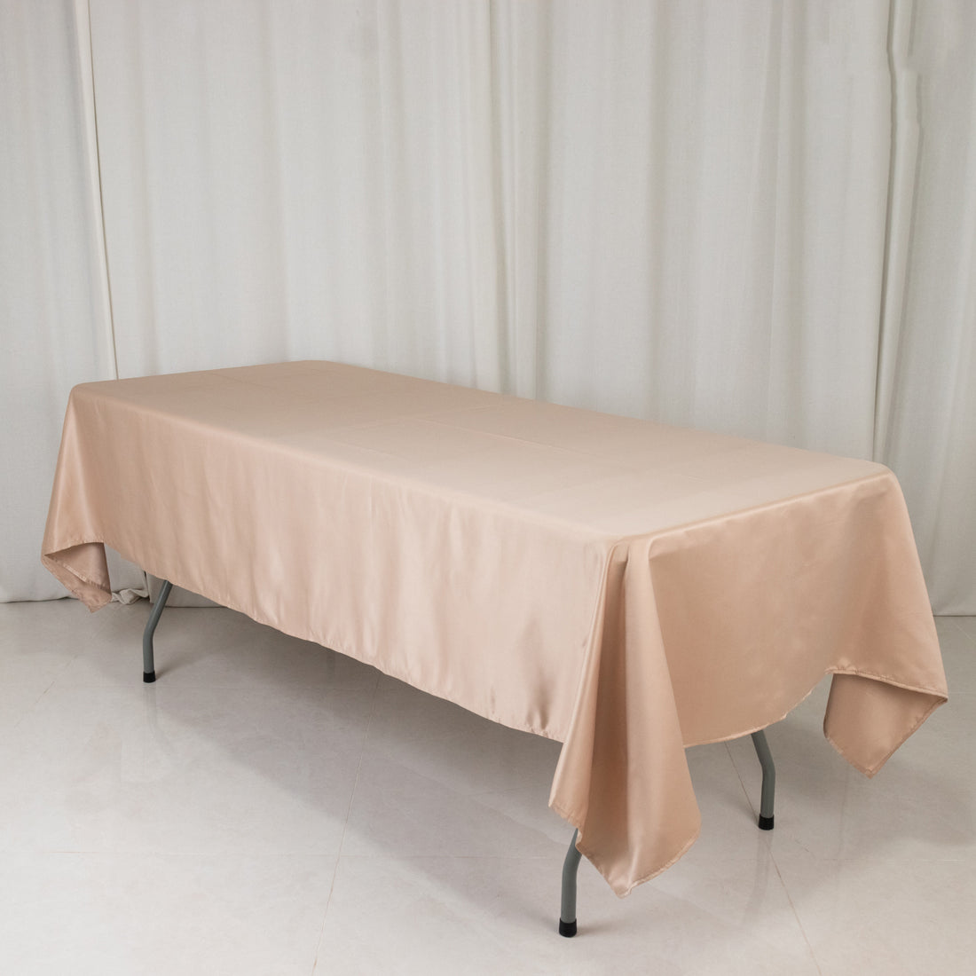 Beige tablecloth draped over a folding table in a studio setting.