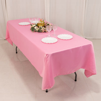 Pink tablecloth draped over a table with plates and decorations.