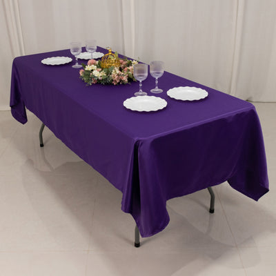 Purple tablecloth draped over a table set with plates and glasses.