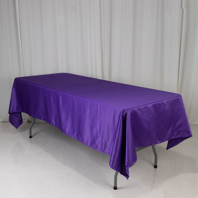 Purple satin tablecloth draped over a folding table in a studio setting.