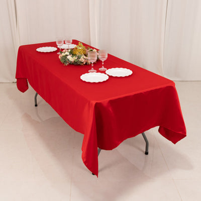 Red tablecloth draped over a table set with plates and glasses.