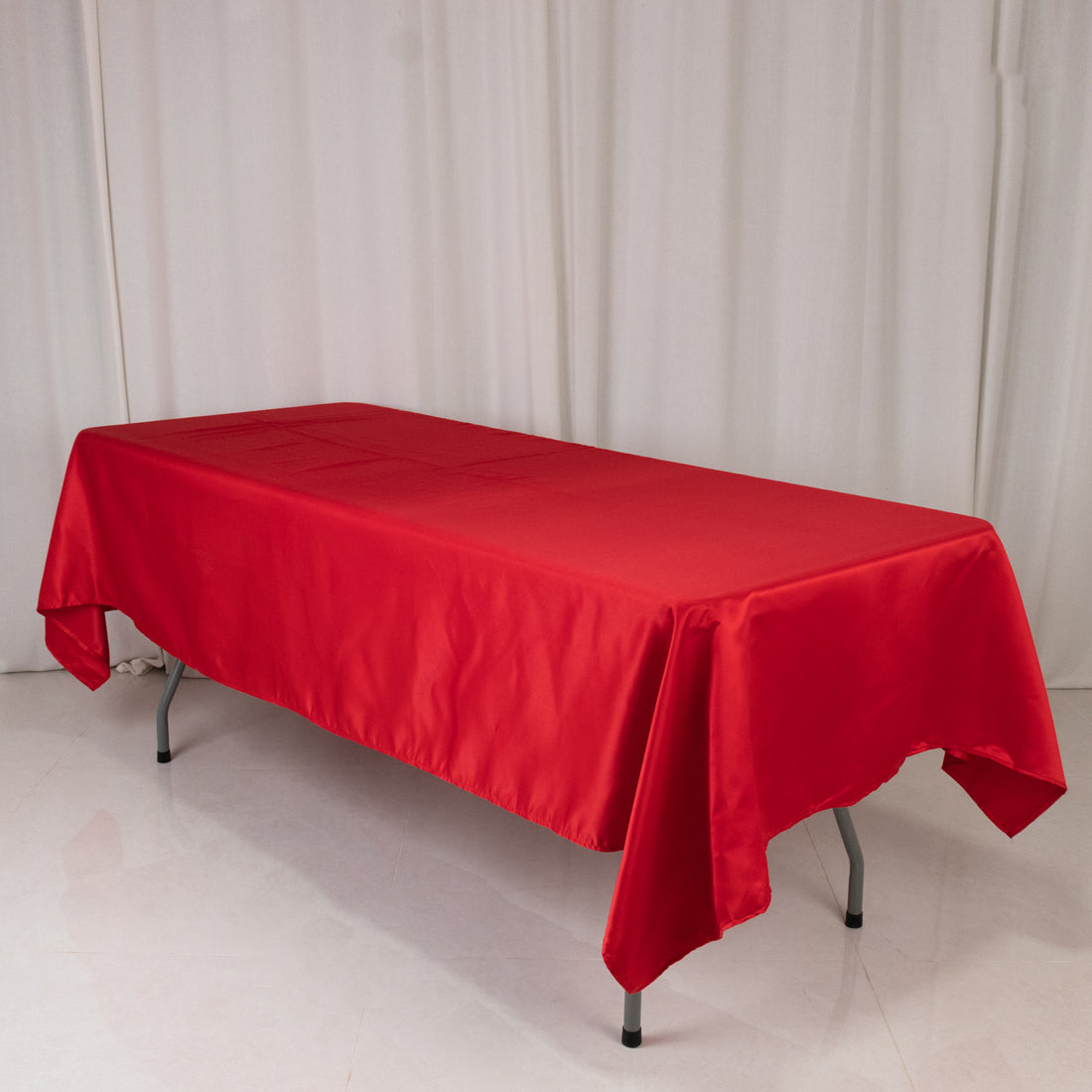 Red tablecloth draped over a folding table in a studio setting.