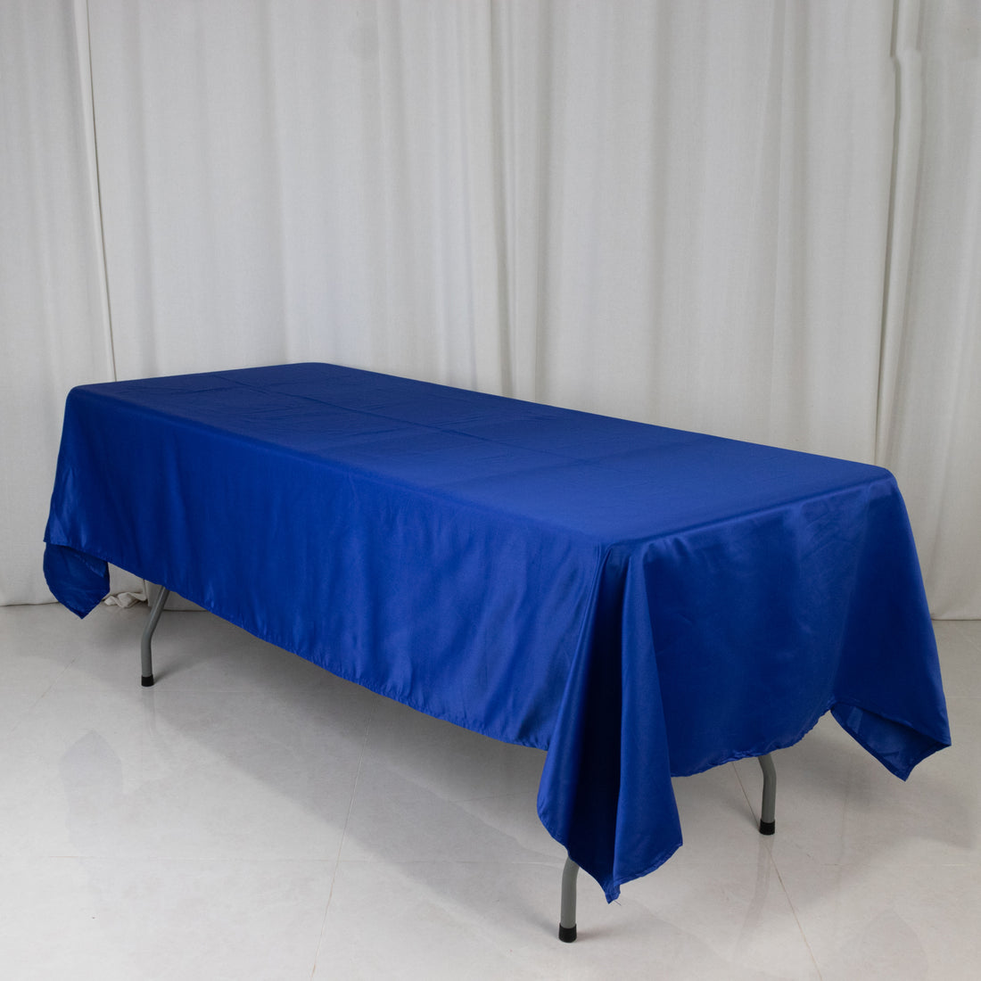Blue tablecloth draped over a table on a plain backdrop.