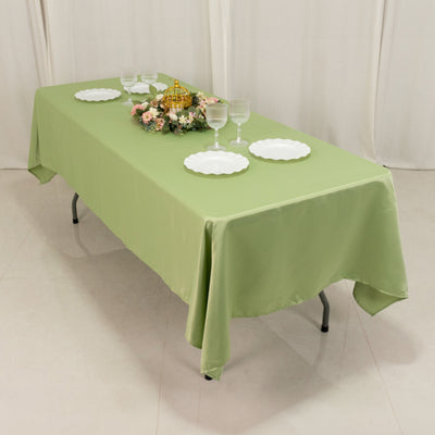 Green tablecloth draped over a table with plates and floral centerpiece.