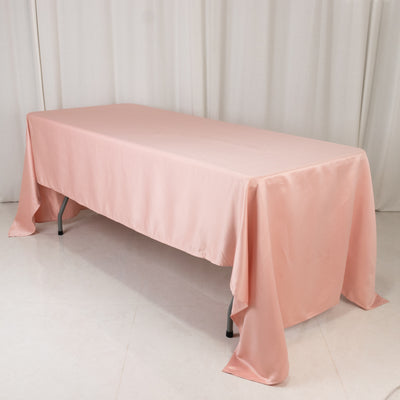 Pink satin tablecloth draped over a folding table in a studio setting.