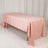 Pink satin tablecloth draped over a folding table in a studio setting.