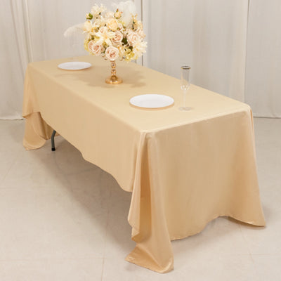Elegant beige tablecloth with plates and floral centerpiece on a dining table.