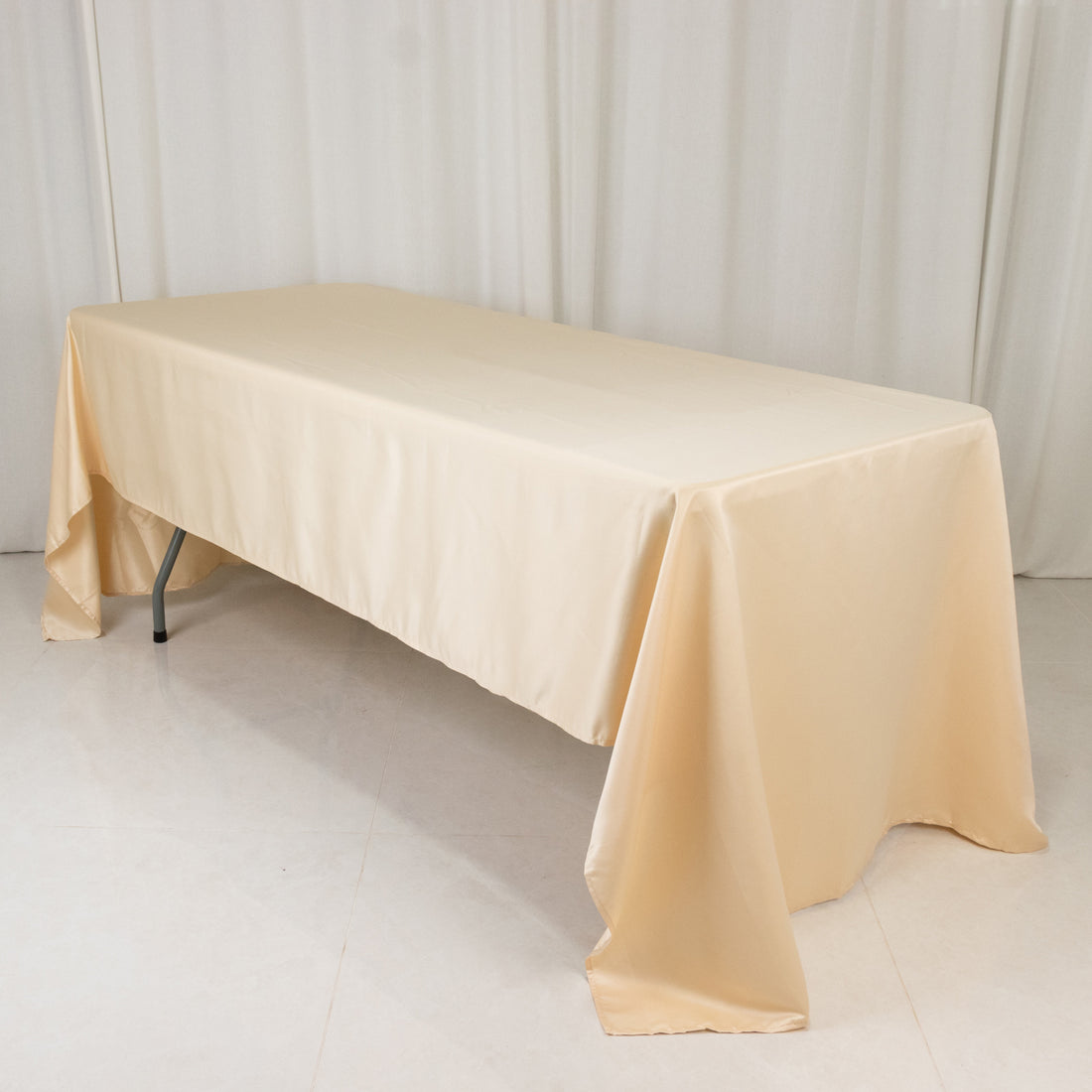 Beige tablecloth draped over a folding table in a studio setting.