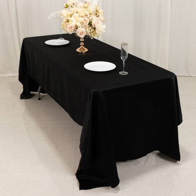 Black tablecloth draped over a long table set for an elegant dining experience.