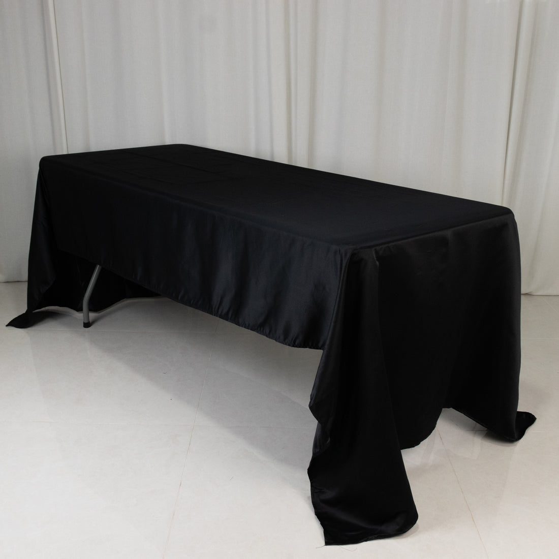 Black satin tablecloth draped over a folding table.