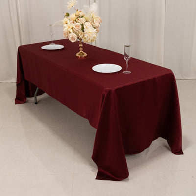 Burgundy tablecloth draped over a table set for dining with floral centerpiece.