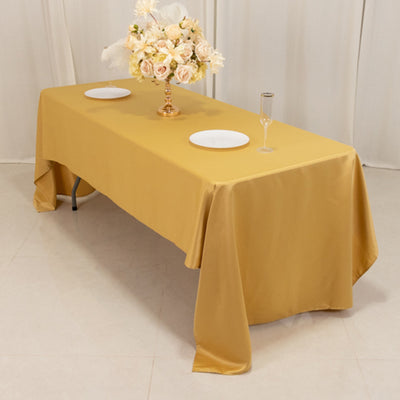 Elegant yellow tablecloth draped over a table with floral centerpiece and dinnerware.