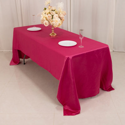 Pink tablecloth draped over a table with plates and a flower centerpiece.