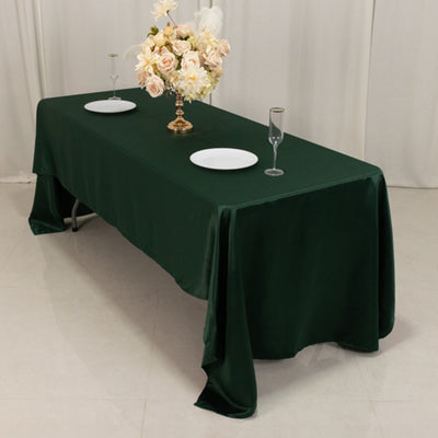 Elegant green tablecloth on a dining table with floral centerpiece and dinnerware.