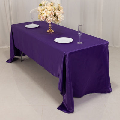 Purple tablecloth draping over a table set with plates and glasses.