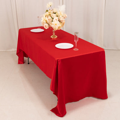 Red tablecloth draped over a table set with plates and a floral centerpiece.