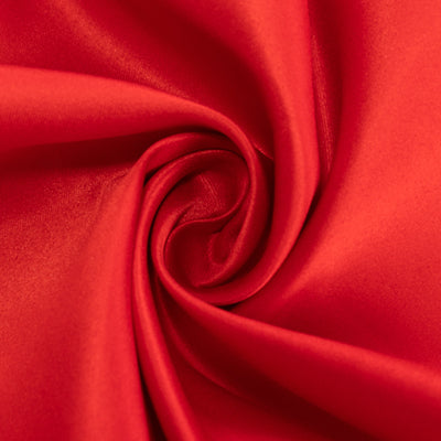 Red satin fabric in a swirl pattern, showcasing its smooth texture.