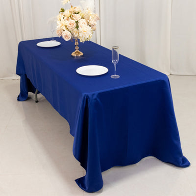 Blue tablecloth draped over a dining table set with plates and a floral centerpiece.