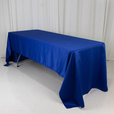 Blue tablecloth draped over a folding table on a white backdrop.