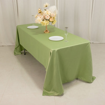 Green tablecloth draped over a table set for a meal with plates and glasses.