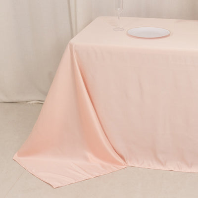 Peach tablecloth draped elegantly over a table with a plate and wine glass.