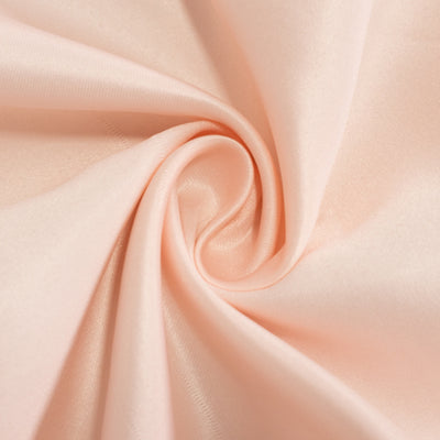 Soft peach satin fabric swirl close-up texture.