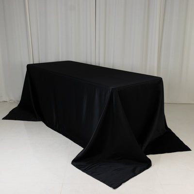 Black table draped with a smooth fabric cover in a minimalistic setting.