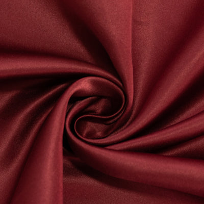 Burgundy satin fabric with smooth, glossy texture in a swirling pattern.