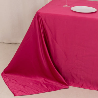 Fuchsia tablecloth draped over a table with a plate and wine glass.