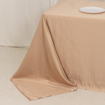 Beige tablecloth draped elegantly over a table with a plate and glass.
