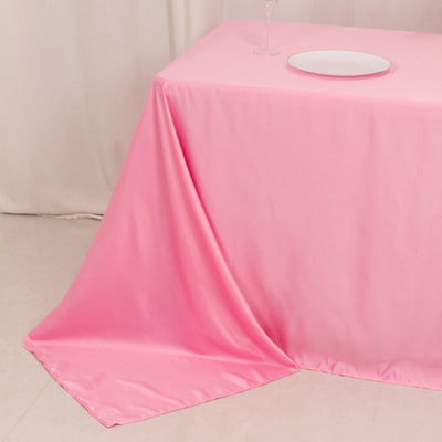Pink tablecloth draped elegantly over a table with a white plate on top.