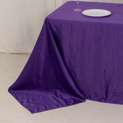 Purple tablecloth draped elegantly over a table with a plate and glass.