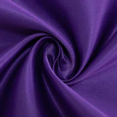 Purple satin fabric swirl close-up showing smooth texture and vibrant color.